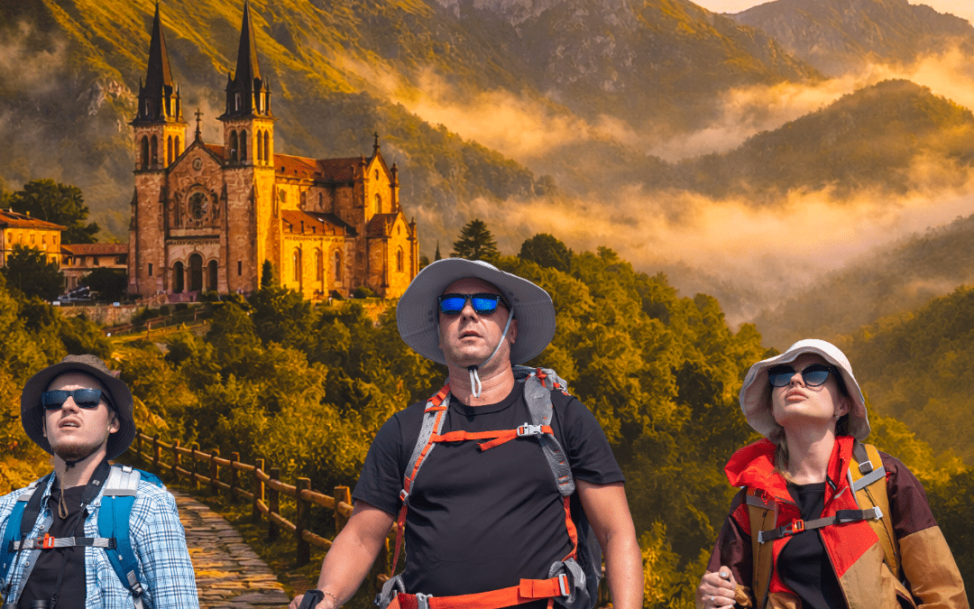 Tres senderistas con mochilas y bastones de trekking caminan por un sendero empedrado en primer plano, con la Basílica de Covadonga iluminada por la luz dorada del amanecer al fondo, rodeada de montañas verdes y niebla en el paisaje de Asturias.